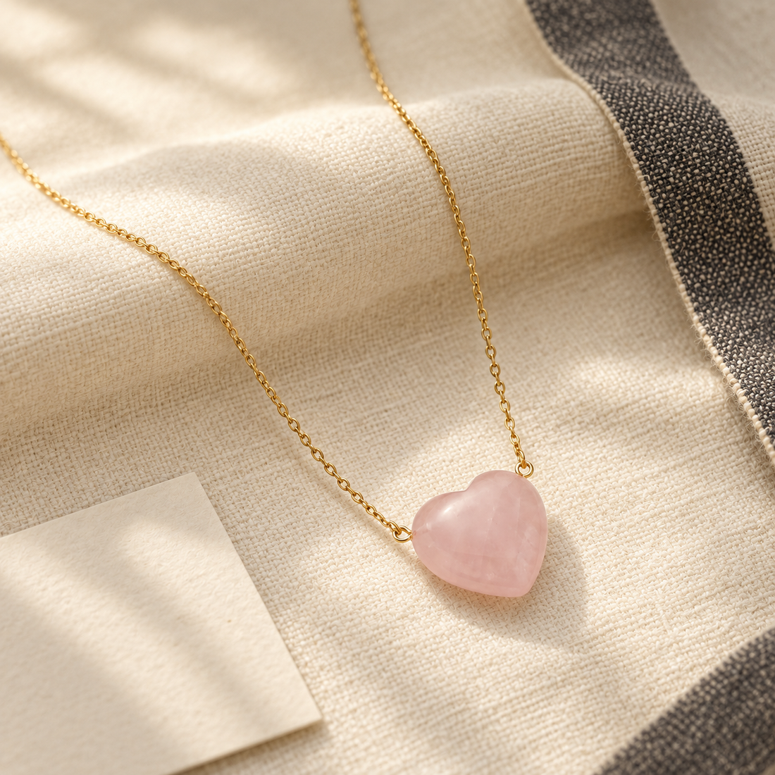 Taurus Venus rose quartz heart pendant styled on ivory handloom fabric in warm natural light
